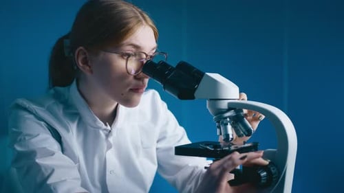 Female Scientist Examining Sample Through Microscope in Lab