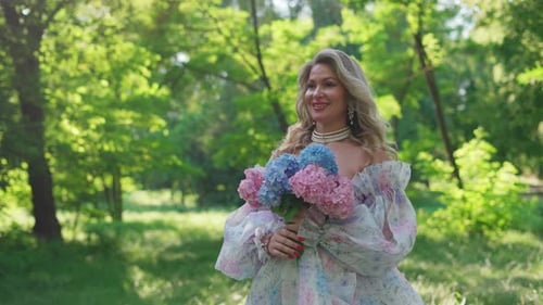 Woman in floral dress holding flowers in park