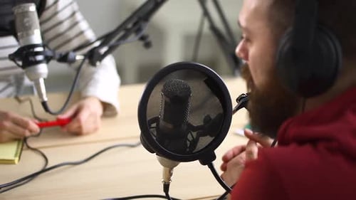 Mann und Frau sprechen während der Radiosendung und sitzen am Tisch im modernen Studio Spbd