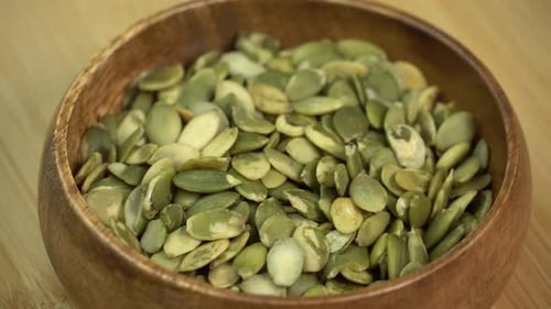 Peeled Pumpkin Seeds Pile Rotating in a Wooden Bowl. Healthy Vegetarian Vegan Raw Food