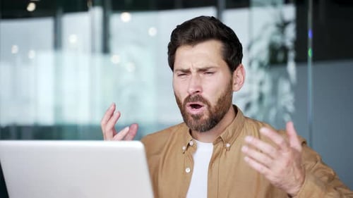 Frustrated Man Working on Laptop in Office