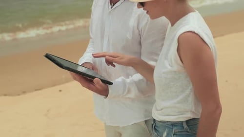 Couple Using Tablet Device on Sandy Beach