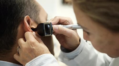 Doctor Examines Patient's Ear with Otoscope in Clinic