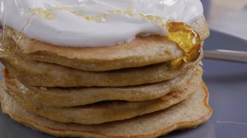 Close-up of a delicious stack of pancakes as honey is drizzled on top.