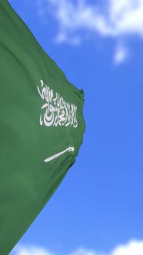 Die Flagge Saudi-Arabiens weht gegen klaren blauen Himmel in einer vertikalen Schleife