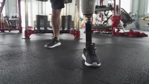 Close up of an athlete's prosthetic leg during workout in the gym with equipment in the background