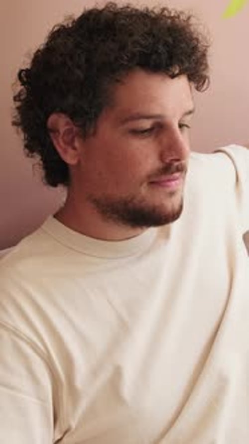 Young Adult Leans Against Wall Smiling