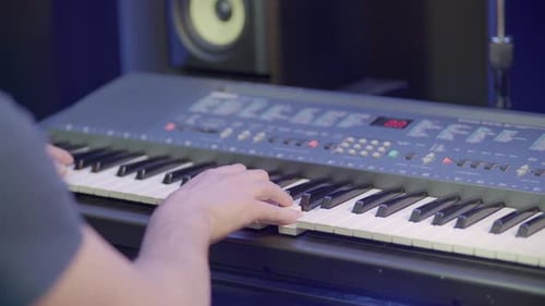 Un músico se sienta al teclado de un piano y toca música.