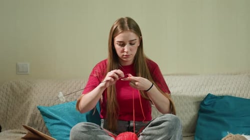 Woman Knitting at Home on Sofa with Yarn