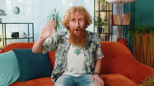 Man with Beard Waving at Camera on Couch
