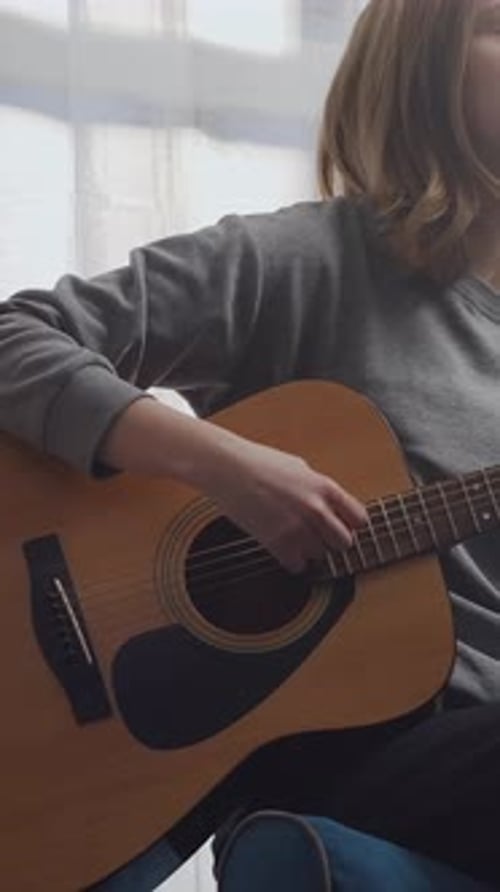 Teen Girl Plays Acoustic Guitar in Room