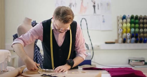 Male Tailor Cutting Fabric in Bright Studio