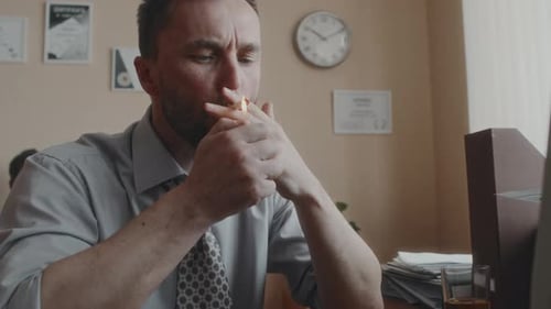 Employé épuisé allumant une cigarette pendant le travail à l'intérieur dans les années 80