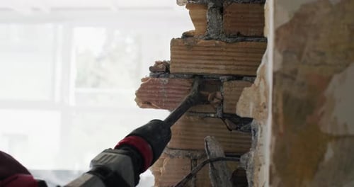 Closeup of the Builder's Hands Dismantling the Wall with a Perforator