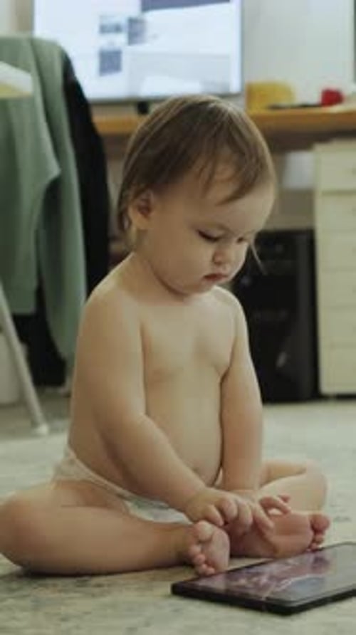 Baby Sitting Looking at a Tablet Indoors