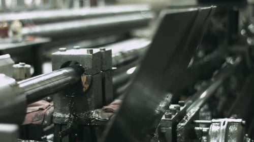 Sliding shot of pipe honing machinery working in a manufacturing plant with steam plume