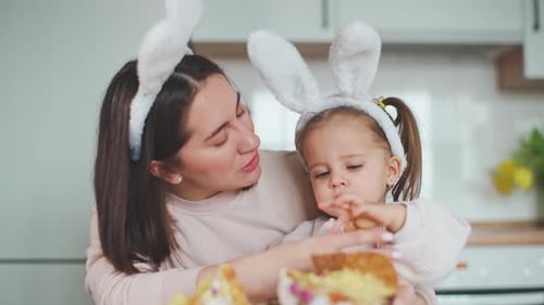 Beautiful daughter and mother are smiling and eating traditional easter cake. Happy Easter
