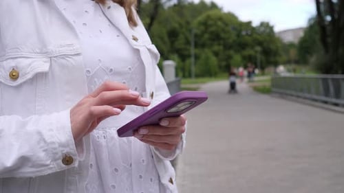 Woman Typing on Phone Outdoors in Park