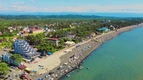Aerial view of sandy beach with colorful umbrellas, people swimming in sea bay