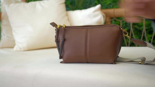 Elegante bolso de cuero marrón exhibido en un acogedor entorno al aire libre