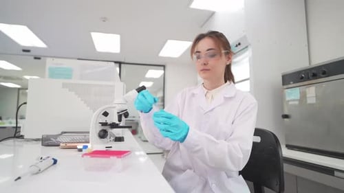 Female Scientist Pipetting Sample in Bright Lab