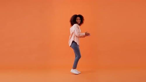 Woman Smiling and Dancing on Orange Background