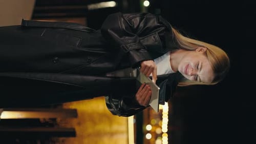 Vertical Video Attractive Lady Standing in the Night City Using Scrolling Tablet