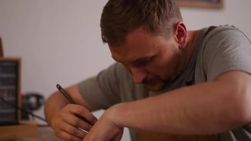 Concentrated Leathersmith Cuts Out Leather Detail at Table