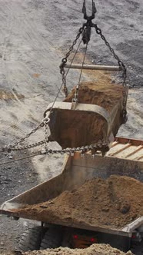 Crane Filling a Dump Truck With Dirt