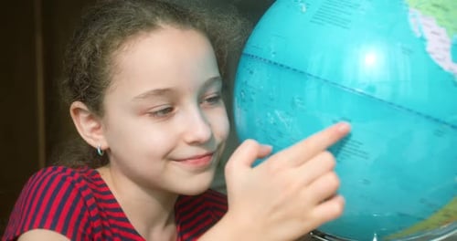 Porträt Nettes Kind blickt lächelnd in die Kamera und hält neben sich einen Globus, Technologie für Schüler