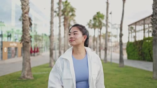 Young Asian Athlete Walking in Slow Motion in a City Park