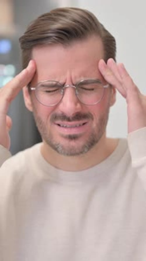 Portrait of Young Man with Headache in Office