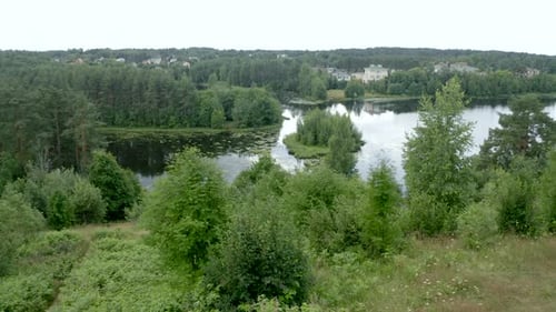 Man Practices Yoga Wheel Pose on Mat on High River Bank