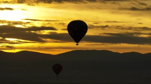 Hot Air Balloons Flying Over Mountains at Sunset
