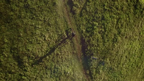 Top-down view of the young athletic man on MTB e-bike pedaling up the hill.