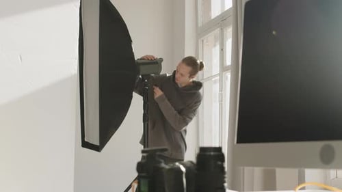 Assistant of Photographer Setting up Lighting Equipment for Studio Photoshoot