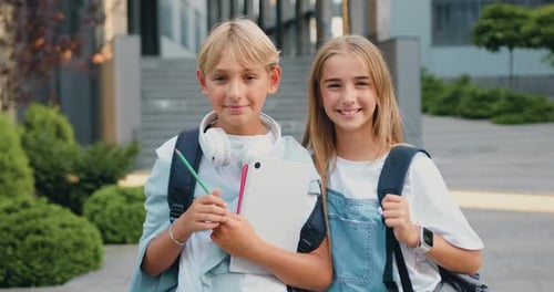 Great elementary school. Happy boy and girl classmates with books and backpack smiling and looking