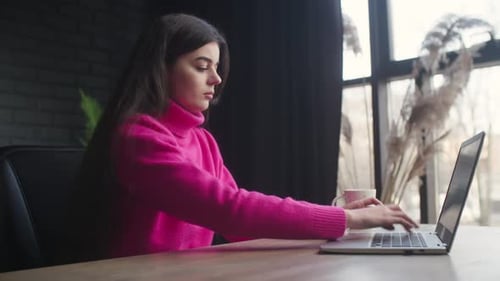 Young Woman Typing on Laptop at Desk Indoors