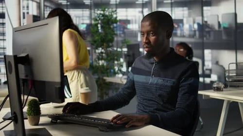 Young Adult Typing on Computer in Modern Office