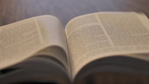 Nahaufnahme einer geöffneten Bibel mit Seiten, die in Zeitlupe wehen