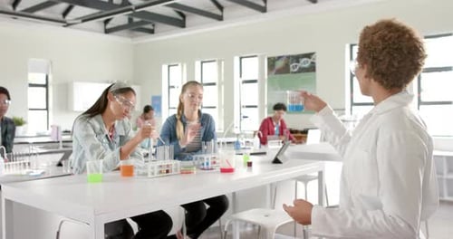 Conducting science experiment, students with teacher in high school laboratory