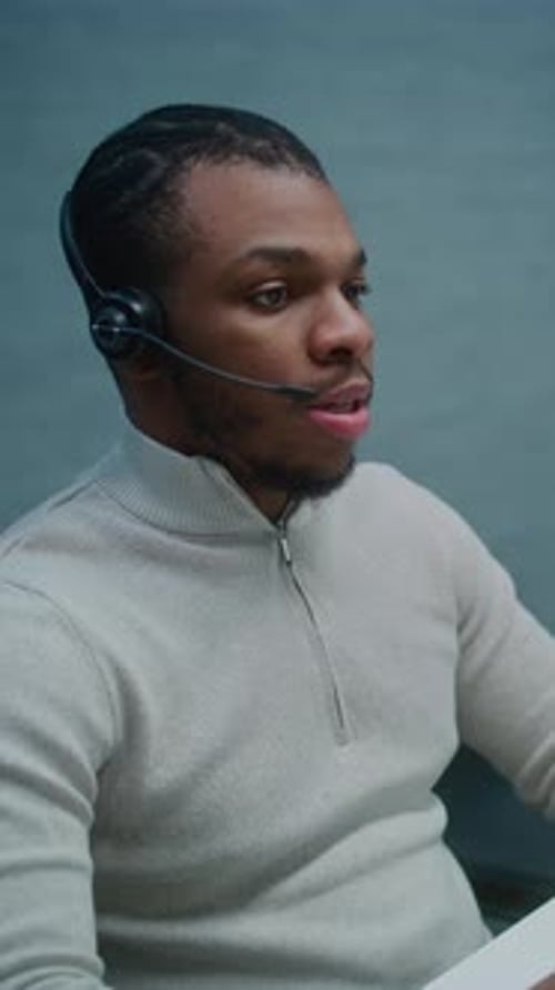 African American Helpdesk Specialist Talks on Headset with Customer Works on Computer