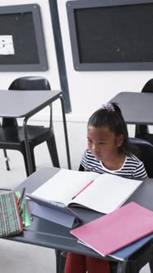Vertical video: In a school setting, a young African American girl raises her hand