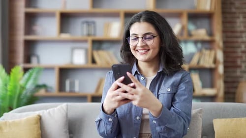 Smiling Young Adult Using Smartphone at Home