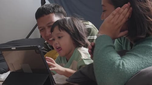 Kleines Mädchen und ihre Eltern genießen es, zu Hause lustige Online-Videos anzusehen, Happy Asian Family Spendin