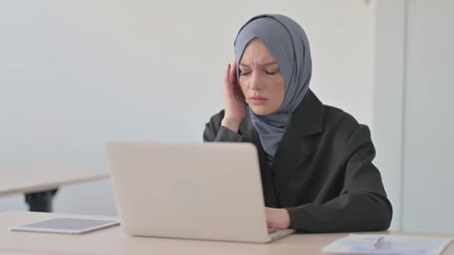 Woman in Hijab Rubbing Temples at Desk