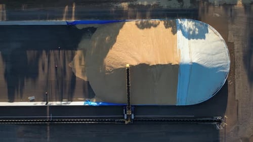 Pile of grain in storage and distribution center. Aerial top-down ascending