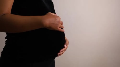 Pregnant woman stroking her belly, standing isolated on white with copyspace. Close-up of expecting