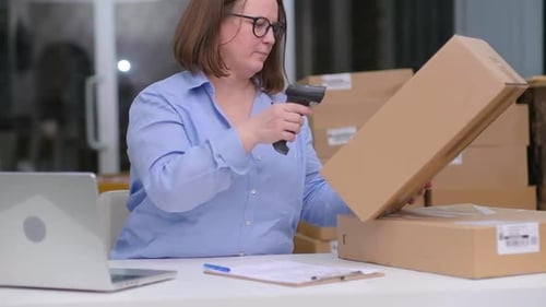 Woman Scanning Barcode on Box in Shipping Warehouse