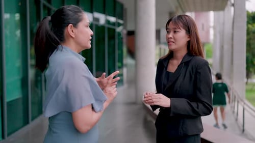 Two confident businesswomen and their colleagues in front of a modern office building, financial inv